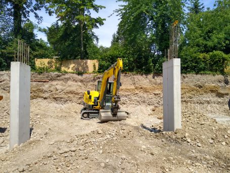 Aushub für Fundamente Tiefgarage Linz 4020 Kettenbagger bei Baggerarbeiten für Fundamente Tiefgarage Linz in der Baugrube zwischen Betonstützen